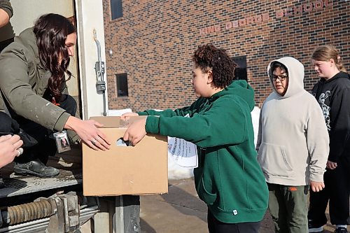 Left: Harvest Manitoba community program director Mika Peterson hands a Meal2Go box over to a King George School student Thursday afternoon. (Abiola Odutola/The Brandon Sun)