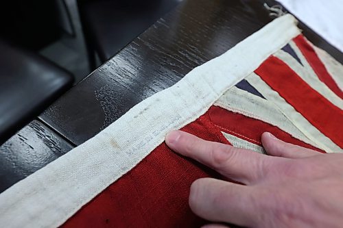 Brandon Mayor Jeff Fawcett points to a barely legible  "Made in England" mark on a Red Ensign flag on Wednesday that once flew at a Brandon school before Canada adopted its current Maple Leaf flag in 1965. (Matt Goerzen/The Brandon Sun)
