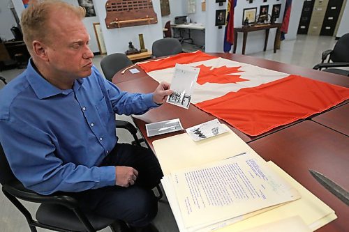 Royal Canadian Artillery Museum director Andrew Oakden holds up one of three photos taken on Feb. 15, 1965 in Brandon at the CFB Shilo park that show the lowering of the former Red Ensign flag, and the raising of the new Maple Leaf flag. All three photos and a copy of the proclamation speech given on the day of the flag raising are stored in the museum's archives. (Photos by Matt Goerzen/The Brandon Sun)