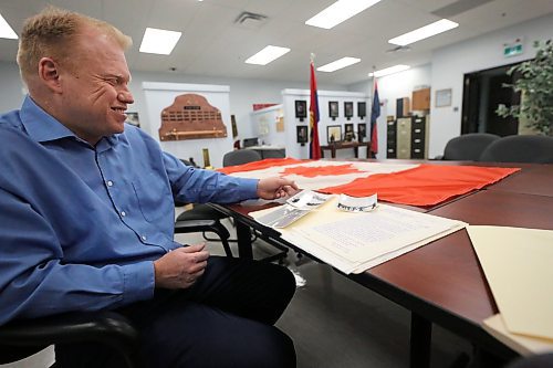 Royal Canadian Artillery Museum director Andrew Oakden talks about three photos taken on Feb. 15, 1965 in Brandon at the base park that show the lowering of the former Red Ensign flag, and the raising of the new Maple Leaf flag. All three photos and a copy of the proclamation speech given on the day of the flag raising are stored in the museum's archives. (Matt Goerzen/The Brandon Sun)