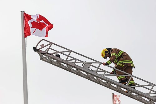 12032025
Devin Gellatly with Brandon Fire and Emergency Services climbs down the ladder after replacing a Canadian flag atop The Dome Building in Brandon on Wednesday afternoon. BFES members took turns at the top of a ladder truck replacing multiple flags at The Dome Building. 
(Tim Smith/The Brandon Sun)default