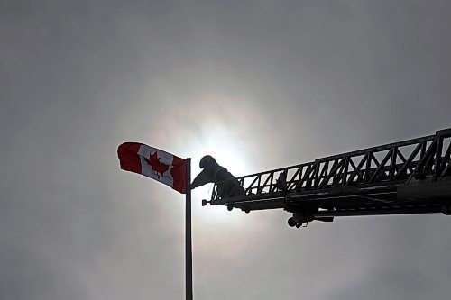 12032025
Devin Gellatly with Brandon Fire and Emergency Services replaces a Canadian flag atop The Dome Building in Brandon on Wednesday afternoon. BFES members took turns at the top of a ladder truck replacing multiple flags at The Dome Building. 
(Tim Smith/The Brandon Sun)default