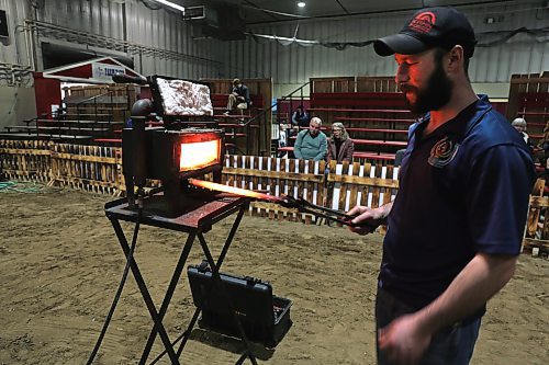 Brad Snyder pulls a bar of steel from his portable forge before his show at the Royal Manitoba Winter Fair. Snyder demonstrated how he forges horseshoes in real-time for a crowd of 60 people. (Connor McDowell/Brandon Sun)