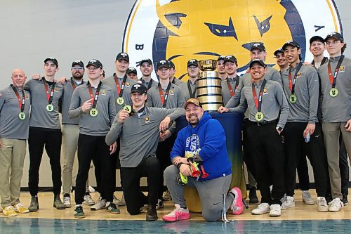 Bailey's Cafe general manager Sean Taron kneels in front of the BU men's volleyball team and the U Sports men's volleyball trophy on Friday. (Thomas Friesen/The Brandon Sun)