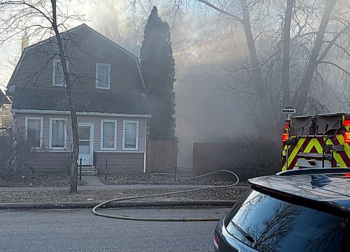 A fire hose is seen leading to the backyard of a home on the 300 block of Seventh Street Wednesday evening as fire crews from Brandon Fire and Emergency Services doused a garage fire. (Michele McDougall/The Brandon Sun)