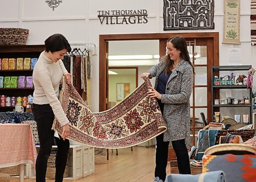Julianna Murray (left), assistant manager at Ten Thousand Villages, examines a handmade fair trade runner rug with store manager Stephanie De la Luz in Brandon on Thursday in preparation of the store's upcoming Fair Trade Rug Event from April 4-22. (Michele McDougall/The Brandon Sun)