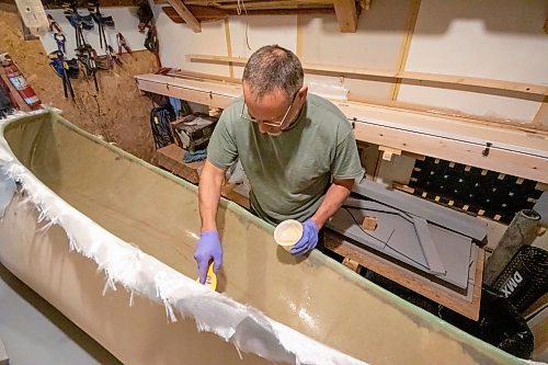 BROOK JONES/FREE PRESS
Paddle and Hum owner Myron Sawatzky builds lightweight solo canoes in a backyard shed he converted into his workshop. The North Kildonan resident is pictured appling epoxy resin to the interior hull of a fiberglass canoe he is building in his workhop in Winnipeg, Man., Monday, May 5, 2025.