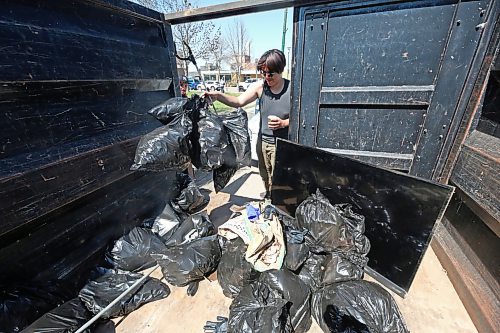 Volunteer Shanahan Genaille drops a bag of garbage he collected into a large refuse bin at Princess Park. (Matt Goerzen/The Brandon Sun)