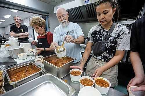 Ulysse Poirier, from left, Sally Bader, Bob, and Angela Daet prepare a meal for fire evacuees who are being housed at Century Arena in Winnipeg on Sunday. (John Woods/Winnipeg Free Press)