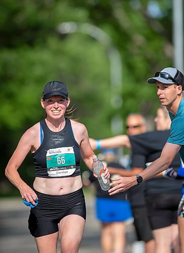 BROOK JONES./ FREE PRESS
Darolyn Walker from East St. Paul, Man., who won the women's half marathon in 2013, 2015 and 2018, grabs pre-filled bottle at a fluids station from her husband Brian Walker, who won the men's full marathon in 2014 and 2021, while she hits the 28km mark along Wellington Crescent as she competes in the full marathon at the 47th Manitoba Marathon in Winnipeg, Man., Sunday, June 15, 2025.