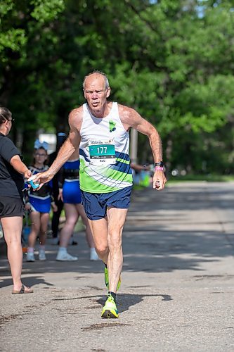 BROOK JONES/FREE PRESS
Bob Cox grabs a cup of water from a volunteer at a fluids station while he hits the 28km mark along Wellington Crescent as he competes in the full marathon during the 47th Manitoba Marathon in Winnipeg, Man., Sunday, June 15, 2025.