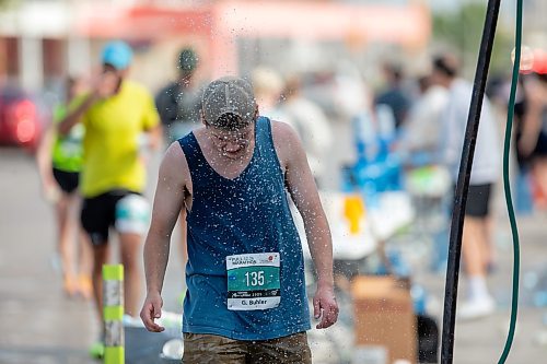 BROOK JONES/FREE PRESS
A full marathoner cools off under a makeshift shower at a fluids station while hitting the 32km mark along Pembina Highway as he competes the 47th Manitoba Marathon in Winnipeg, Man., Sunday, June 15, 2025.