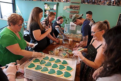 Volunteers from Brandon Fire and Emergency Services and the Brandon Public-Safety Communications Centre work to package 330 green heart-shaped sugar cookies at Chez Angela Bakery and Café in Brandon on Thursday. This was the second of three rounds of heart cookie batches sold by Chez Angela in support of the family of Chinonso Onuke, the Grade 10 student from École secondaire Neelin High School who was attacked in the school and seriously injured earlier this month. All of the money raised will be going toward expenses incurred by the family of the student. (Tim Smith/The Brandon Sun)
