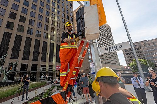 MIKE DEAL / FREE PRESS
construction crews remove the last of the barriers while impatient pedestrians cross the street at Portage Avenue and Main Street just hours before they officially open Friday morning.
20250627 - June 27, 2025