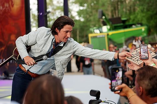 Drake Milligan of Texas grabs a sign from a fan while performing with his band on the main stage at Dauphin’s Countryfest 2025 on Friday evening. (Tim Smith/The Brandon Sun)
