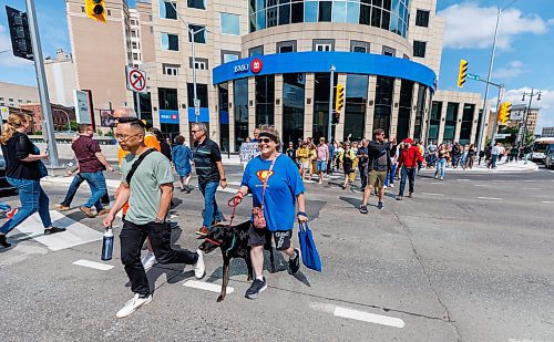 MIKE DEAL / FREE PRESS
Once crossing the street at Portage and Main became official huge crowds of people make their way around to each of the crosswalks, including Andrea Kohuch with her dog, Arby.
The day of the official opening of the pedestrian crosswalks at the historic intersection of Portage Avenue and Main Street started with crews clearing away the last of the barriers and impatient people crossing despite those barriers.
The Mayor, Scott Gillingham and several city council members, along with may of the stakeholders for the buildings at each of the corners of the intersection were on hand with several hundred members of the public who cam to cheer and be some of the first to cross after the opening.
Dancing Gabe was on hand to lead a huge crowd around each of the intersections.
Reporter: Tyler Searle
250627 - Friday, June 27, 2025.