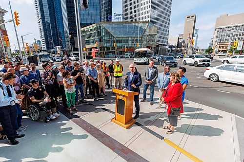 MIKE DEAL / FREE PRESS
Mayor Scott Gillingham speaks to the assembled crowd before walking across the street making the official opening of the pedestrian crosswalks.
The day of the official opening of the pedestrian crosswalks at the historic intersection of Portage Avenue and Main Street started with crews clearing away the last of the barriers and impatient people crossing despite those barriers.
The Mayor, Scott Gillingham and several city council members, along with may of the stakeholders for the buildings at each of the corners of the intersection were on hand with several hundred members of the public who cam to cheer and be some of the first to cross after the opening.
Dancing Gabe was on hand to lead a huge crowd around each of the intersections.
Reporter: Tyler Searle
250627 - Friday, June 27, 2025.