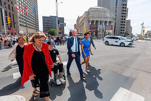 MIKE DEAL / FREE PRESS
Mayor Scott Gillingham along with several city council members and stakeholders cross Main Street to mark the official opening of the pedestrian crosswalks.
The day of the official opening of the pedestrian crosswalks at the historic intersection of Portage Avenue and Main Street started with crews clearing away the last of the barriers and impatient people crossing despite those barriers.
The Mayor, Scott Gillingham and several city council members, along with may of the stakeholders for the buildings at each of the corners of the intersection were on hand with several hundred members of the public who cam to cheer and be some of the first to cross after the opening.
Dancing Gabe was on hand to lead a huge crowd around each of the intersections.
Reporter: Tyler Searle
250627 - Friday, June 27, 2025.