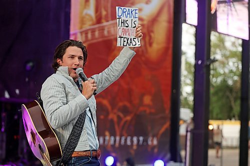 27062025
Drake Milligan of Texas shows off a sign from a fan while performing with his band on the main stage at Dauphin&#x2019;s Countryfest 2025 south of Dauphin, Manitoba on a hot Friday evening. 
(Tim Smith/The Brandon Sun)