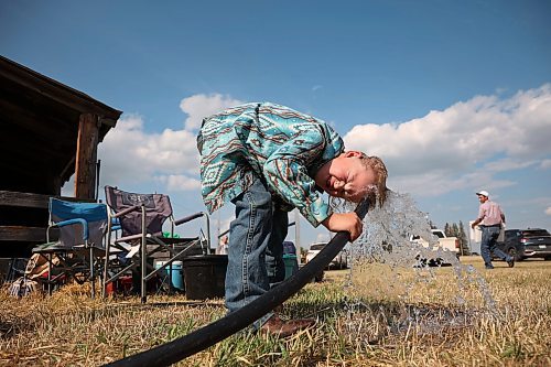 Ten-year-old Castleton Scott of Ashern soaks his head with water from a hose to cool down. (Tim Smith/The Brandon Sun)