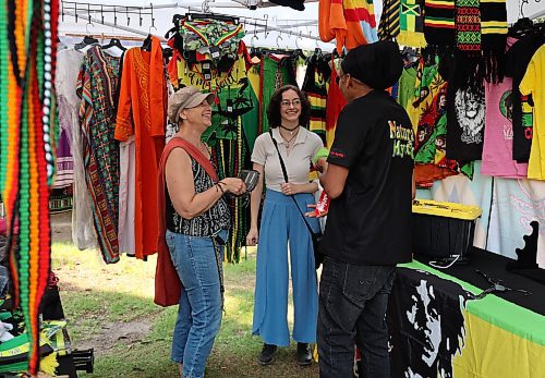Warren Benns, owner of Natural Mystic shares a laugh with Stacey and Izzy Eaton at the Naija Market in Princess Park Saturday afternoon in downtown Brandon. (Michele McDougall/The Brandon Sun)