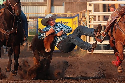 24072025
Tate Beierbach of Maple Creek, Sk slides off his horse to bring down a steer during the steer wrestling event at the opening go round of the Manitoba Threshermen’s Reunion &amp; Stampede rodeo at Austin, Manitoba on Thursday evening. 
(Tim Smith/The Brandon Sun)