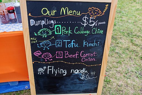 BROOK JONES/FREE PRESS
Aaron Li, who moved to Winnipeg with his family in 2022, markets Chinese dumplings based on family recipes and sells his dumplins at the Wolseley Farmers Market at Saint Margaret's Anglican Church in Winnipeg, Man. Pictured: A menu board lists a variety of dumplings such as pork with cabbage and chive, tofu with kimchi and beef with carrots and onion at Li's Super Flying Dumpling booth during the Wolseley Farmers Market Tuesday, July 29, 2025.