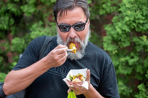 BROOK JONES/FREE PRESS
Aaron Li, who moved to Winnipeg with his family in 2022, markets Chinese dumplings based on family recipes and sells his dumplins at the Wolseley Farmers Market at Saint Margaret's Anglican Church in Winnipeg, Man. Li has a variety of dumplings such as pork with cabbage and chive, tofu with kimchi and beef with carrots and onion. Pictured: Winnipeg resident Curt Gottwald, 52, enjoys a batch of dumplings from Li's Super Flying Dumpling booth during the Wolseley Farmers Market Tuesday, July 29, 2025.