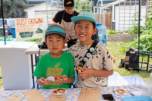 BROOK JONES/FREE PRESS
Aaron Li, who moved to Winnipeg with his family in 2022, markets Chinese dumplings based on family recipes and sells his dumplins at the Wolseley Farmers Market at Saint Margaret's Anglican Church in Winnipeg, Man. Li has a variety of dumplings such as pork with cabbage and chive, tofu with kimchi and beef with carrots and onion. Li's children Jasper Li, 6, (left) and Oscar Li, 8, put Super Flying Dumpling logo stickers on paper bags while helping out their dad, who is pictured in the background preparing dumplings, at Li's Super Flying Dumpling booth during the Wolseley Farmers Market Tuesday, July 29, 2025.