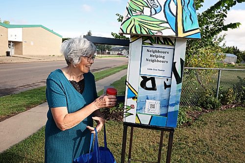 Sylvia Barr stocks the Little Free Pantry she started on 10th Street across from École Secondaire Neelin High School in Brandon on Wednesday morning. (Tim Smith/The Brandon Sun)