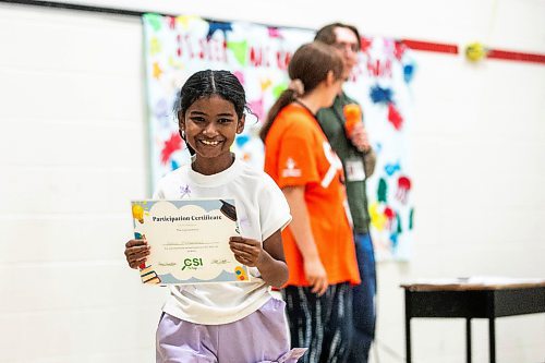 MIKAELA MACKENZIE / FREE PRESS
	
Asma Mohammed (going into grade five) holds up her participation certificate at the CSI Summer Learning Enrichment Program graduation ceremony at Sister MacNamara on Wednesday, Aug. 6, 2025. The CSI program offers educational and recreational programming for five weeks in the summer.

Standup.
Winnipeg Free Press 2025