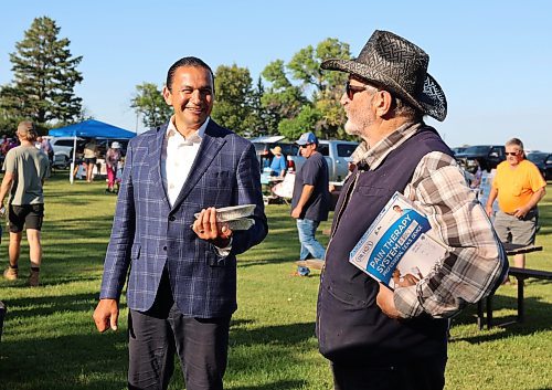 Premier Wab Kinew speaks with a vendor while holding saskatoon and cherry pies he just bought at the Deleau Farmer's Market on Thursday. (Alex Lambert/The Brandon Sun)