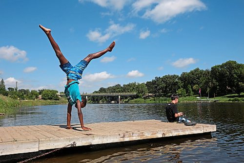 19082025
Kai Denbow walks on his hands as his friend Nathan Holden fishes from a dock along the Souris River in Souris on a hot Tuesday.
(Tim Smith/The Brandon Sun)