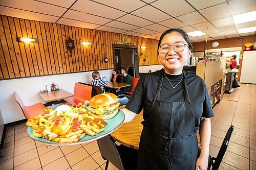 MIKAELA MACKENZIE / FREE PRESS
	
Wynnie Doan, co-owner of Vickie's Snack Bar, with a cheeseburger and volcano poutine in Beausejour on Tuesday, Aug. 19, 2025. 

For Dave Sanderson story.
Winnipeg Free Press 2025