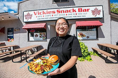 MIKAELA MACKENZIE / FREE PRESS
Wynnie Doan, co-owner of Vickie's Snack Bar, with a cheeseburger and volcano poutine in Beausejour on Tuesday, Aug. 19, 2025.
For Dave Sanderson story.
Winnipeg Free Press 2025