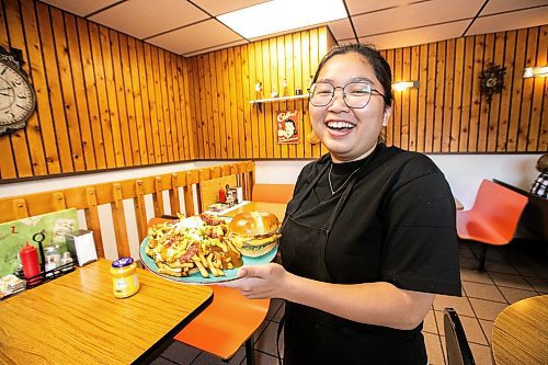 MIKAELA MACKENZIE / FREE PRESS
	
Wynnie Doan, co-owner of Vickie's Snack Bar, with a cheeseburger and volcano poutine in Beausejour on Tuesday, Aug. 19, 2025. 

For Dave Sanderson story.
Winnipeg Free Press 2025