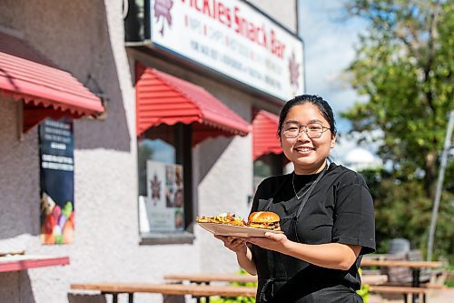 MIKAELA MACKENZIE / FREE PRESS
Wynnie Doan, co-owner of Vickie's Snack Bar, with a cheeseburger and volcano poutine in Beausejour on Tuesday, Aug. 19, 2025.
For Dave Sanderson story.
Winnipeg Free Press 2025
