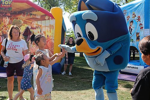 Moon and Sissi play with the Bluey mascot at the Brandon and District Labour Council's annual free barbecue at Stanley Park on Monday. (Skye Anderson/The Brandon Sun)