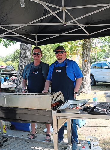 Dustin Rogers and Dean Rodwell barbecue hotdogs for the Brandon and District Labour Council's annual free barbecue at Stanley Park on Monday. (Skye Anderson/The Brandon Sun)