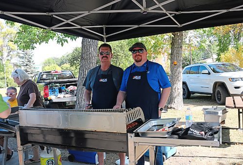 Dustin Rogers and Dean Rodwell barbecue hotdogs for the Brandon and District Labour Council's annual free barbecue at Stanley Park on Monday. (Skye Anderson/The Brandon Sun)