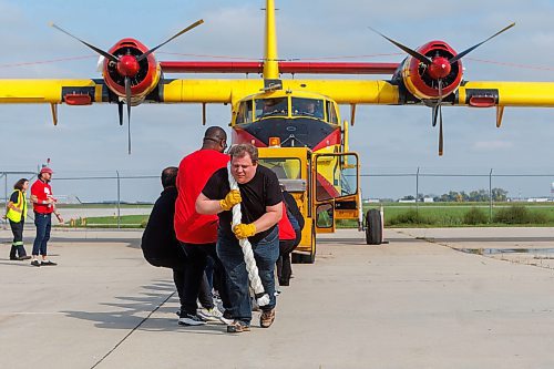 MIKE DEAL / FREE PRESS
James Finkbeiner (centre) an employee with law firm Taylor McCaffrey heaves on the end of the rope pulling (along with fellow employees) a Canadair CL215 (Scooper) which weighs approximately 27,000 pounds empty.
Participants take part in the United Way Winnipeg’s Plane Pull at the RRC Polytech Stevenson Campus-Winnipeg Friday morning to celebrate the organizations 60th fundraising campaign.
Reporter: Kevin Rollason
250912 - Friday, September 12, 2025.