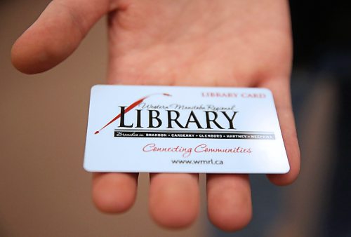 Alex Rogowsky, manager of programming and community services for the Western Manitoba Regional Library, holds a library card in his outstretched hand. (Matt Goerzen/The Brandon Sun)