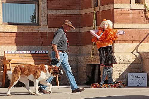 A pedestrian and their dog pass by a dressed-up scarecrow in Souris on Wednesday. Scarecrow Days, the town's annual festival, runs from Friday until Sunday and features a variety of events, including the scarecrow competition, a town-wide yard sale, a barbecue, a car show, and other entertainment and events. (Tim Smith/The Brandon Sun)
