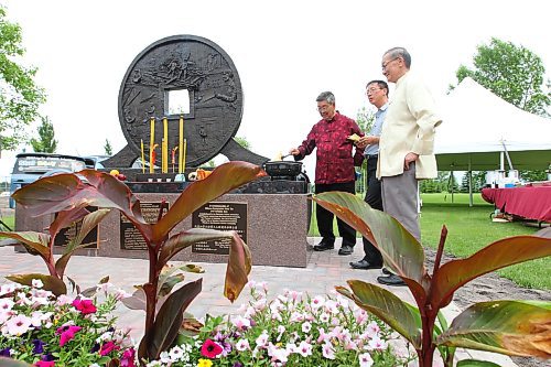 Project co-ordinator Kenny Choy and advisory committee members Sergio Lee and Yuen Toi Ng burn ceremonial money during the unveiling of the Chinese head tax monument at the Brandon Municipal Cemetery in 2011. (Tim Smith/Brandon Sun files)