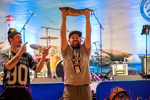 BROOK JONES/FREE PRESS
Vancouver, B.C., resident Shane Shepherd (right) holds up an Atlantic cod named Louis as Edmonton, Alta., resident Steve Hedley points to the fish as they prepare for a Screech-In ceremony while they are pictured inside the Team Party Room - Eastern Social Hall at the Grey Cup Festival Hub at the RBC Convention Centre in Winnipeg, Man., Thursday, Nov. 13, 2025.