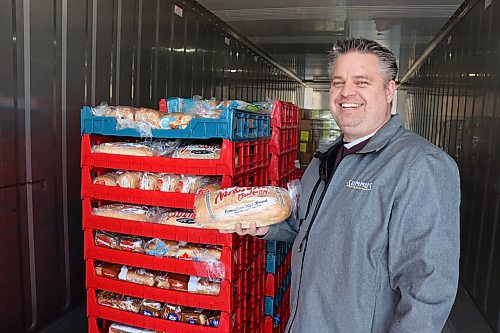 John Howard Society of Brandon chair Ted Dzogan holds up a loaf of bread inside one of the Food Rescue Grocery Store's refrigerated storage units in 2023. The not-for-profit business's use of shipping containers as refrigerated storage units has spread to Winnipeg under a charity that just installed two. (Kyle Darbyson/The Brandon Sun)