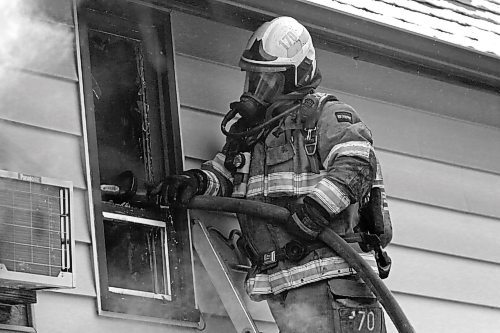 A Brandon firefighter pumps water into the side window of a burning house in the 600 block of 16th Street on Friday afternoon. Police on scene said the first may have started in the garage, but the cause was not officially known on Friday afternoon. Billowing black and grey smoke could be seen for several blocks around the structure, which was a complete loss as a result of the blaze. A Brandon Police officer on scene said no one was injured in the fire. (Matt Goerzen/The Brandon Sun)