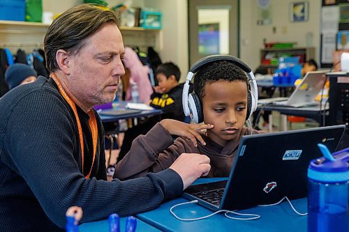 MIKE DEAL / FREE PRESS
Yoas Degefu, wearing headphones, listens and reads to a graphic novel while his teacher Russell Miller supervises.
Yoas is Ethiopian and has only been here for about a month. His teacher, Russell Miller, will occasionally use AI to communicate in Amharic with him.
Russell Miller’s grade four class at Greenway School, 390 Burnell Street, where AI has come into play to help some students learn to read and for communication with some students who’s first language isn’t English.
Reporter: Maggie Macintosh
251209 - Tuesday, December 09, 2025.