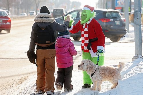 The Grinch, aka Jennifer Botham, walks her dog Romio along 18th Street in Brandon, waving to passing vehicles and spreading Christmas cheer on Monday. (Tim Smith/The Brandon Sun)