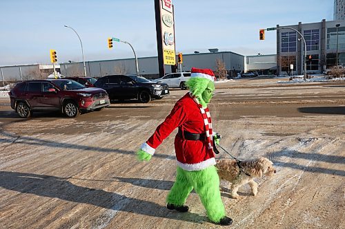15122025
The Grinch, aka Jennifer Botham, walks her dog Romio along 18th Street in Brandon, waving to passing vehicles and spreading Christmas cheer on Monday. 
(Tim Smith/The Brandon Sun)